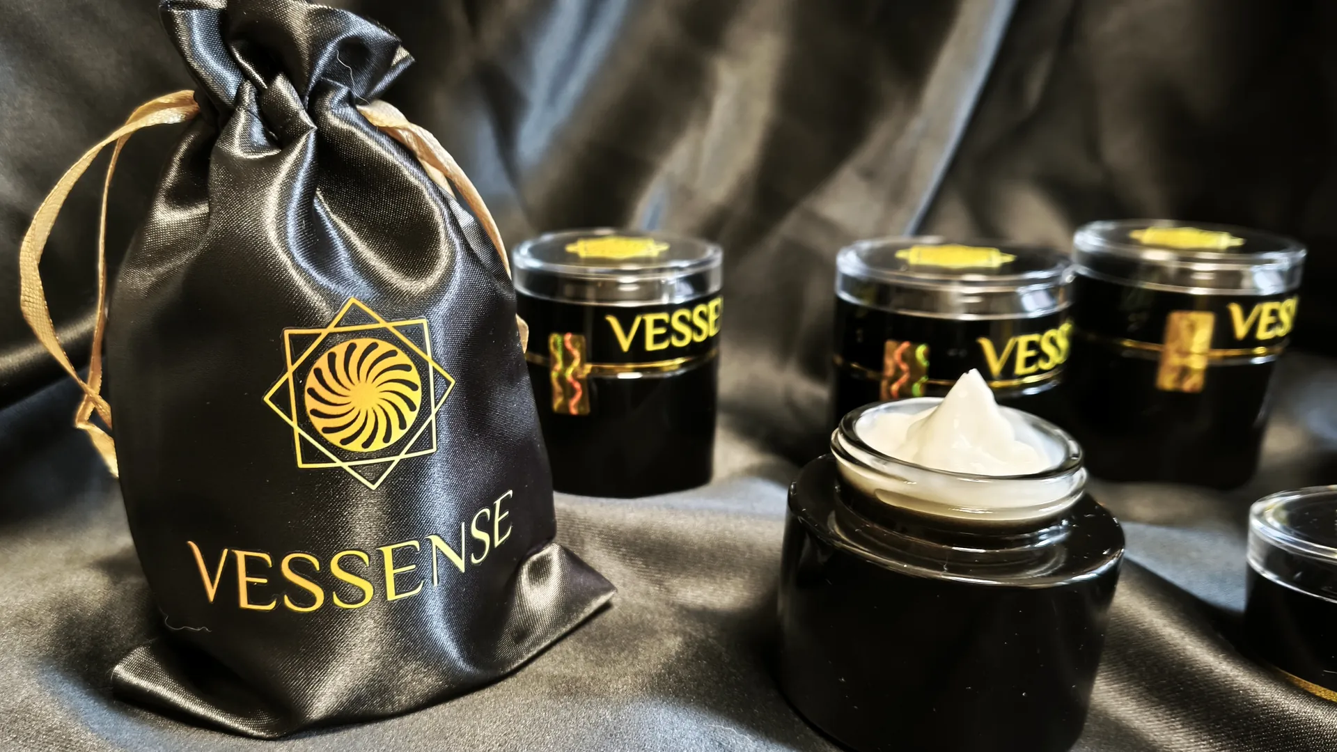 Vasetti VESSENSE e custodia di presentazione disposti su raso nero.